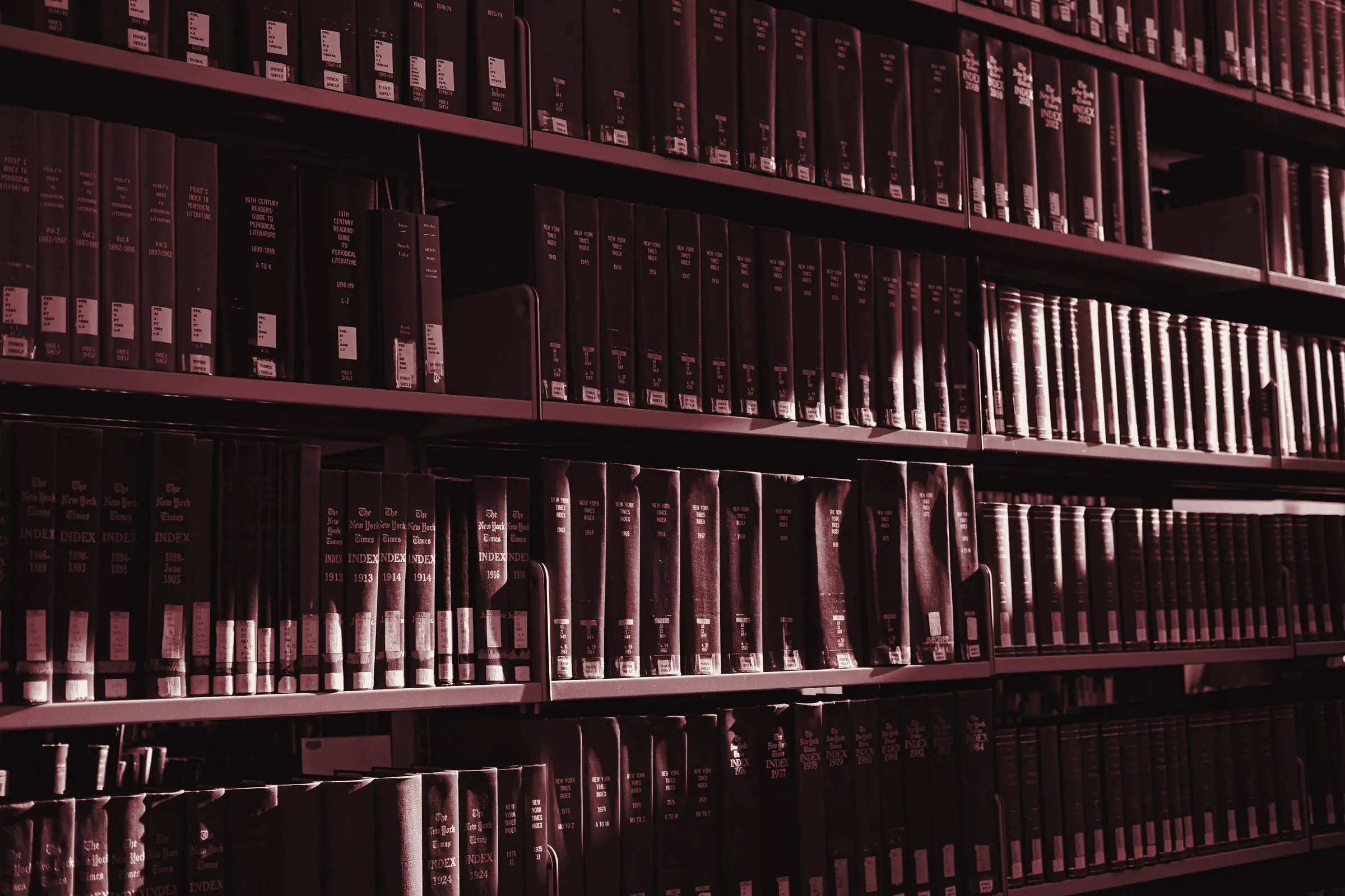 Scaffali di una biblioteca con volumi rilegati in rosso bordeaux e grigio